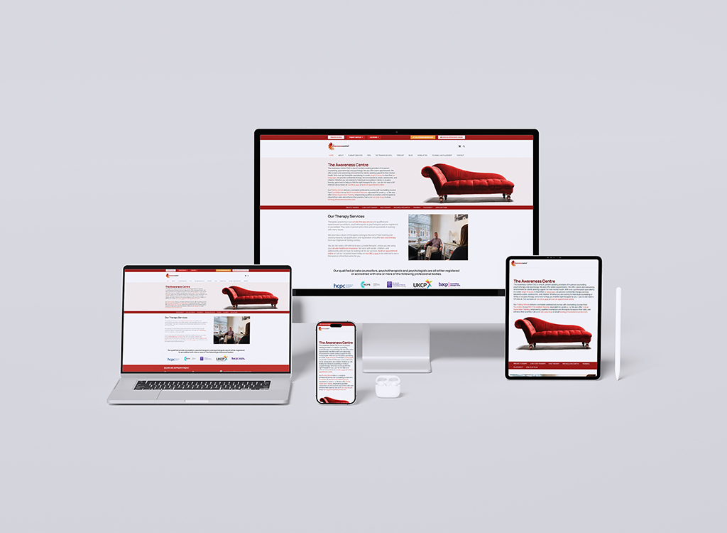 Image showcasing a responsive website design for The Awareness Centre, displayed on multiple devices including a desktop, laptop, tablet, and smartphone. The pages feature information about therapy services and a prominent red chaise lounge image. Ideal for promoting mental health services online.